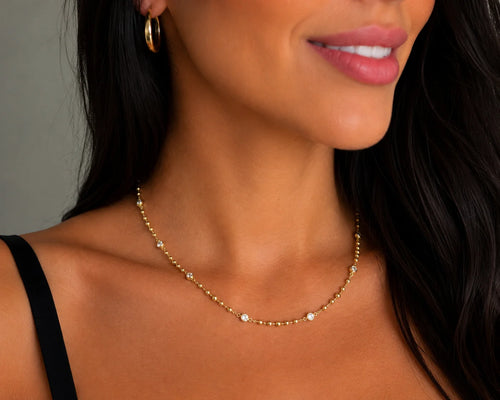 Woman wearing 18k gold filled beaded CZ necklace at collarbone, bezel stations
