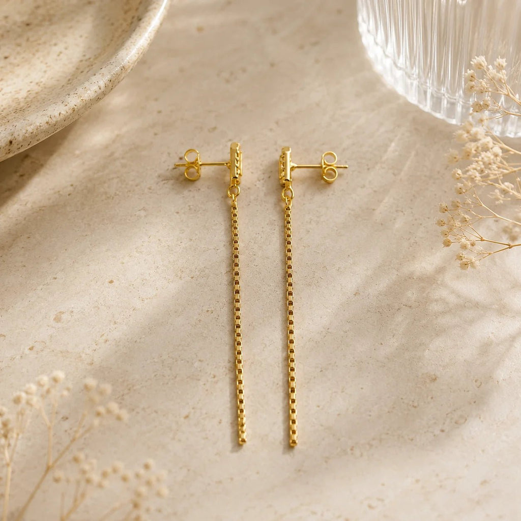 Close-up of Cascade pavé CZ chain drop earrings on cream fabric