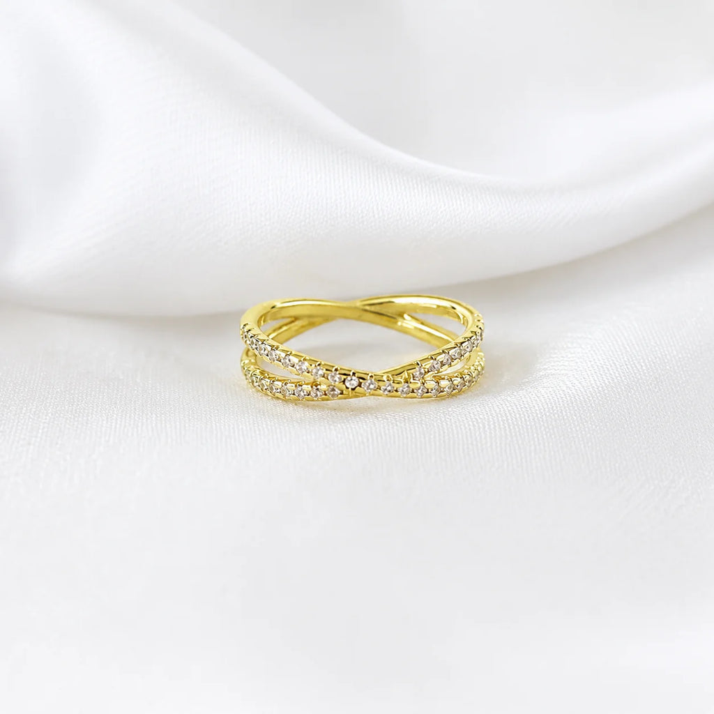 CZ X ring in 18k gold filled lying on white silk, crossover pavé band