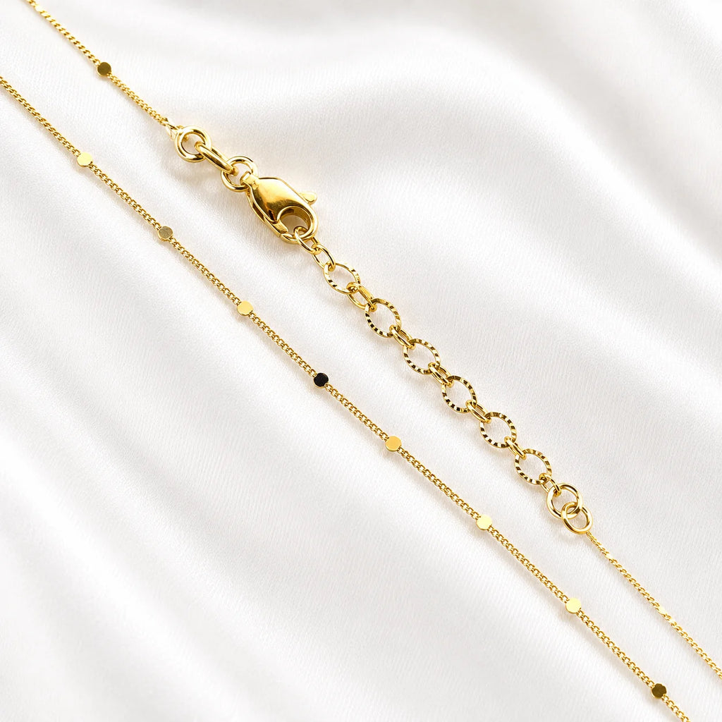 Flat lay of Ma Vie dainty curb chain necklace on cream silk, 18k gold filled pressed detail