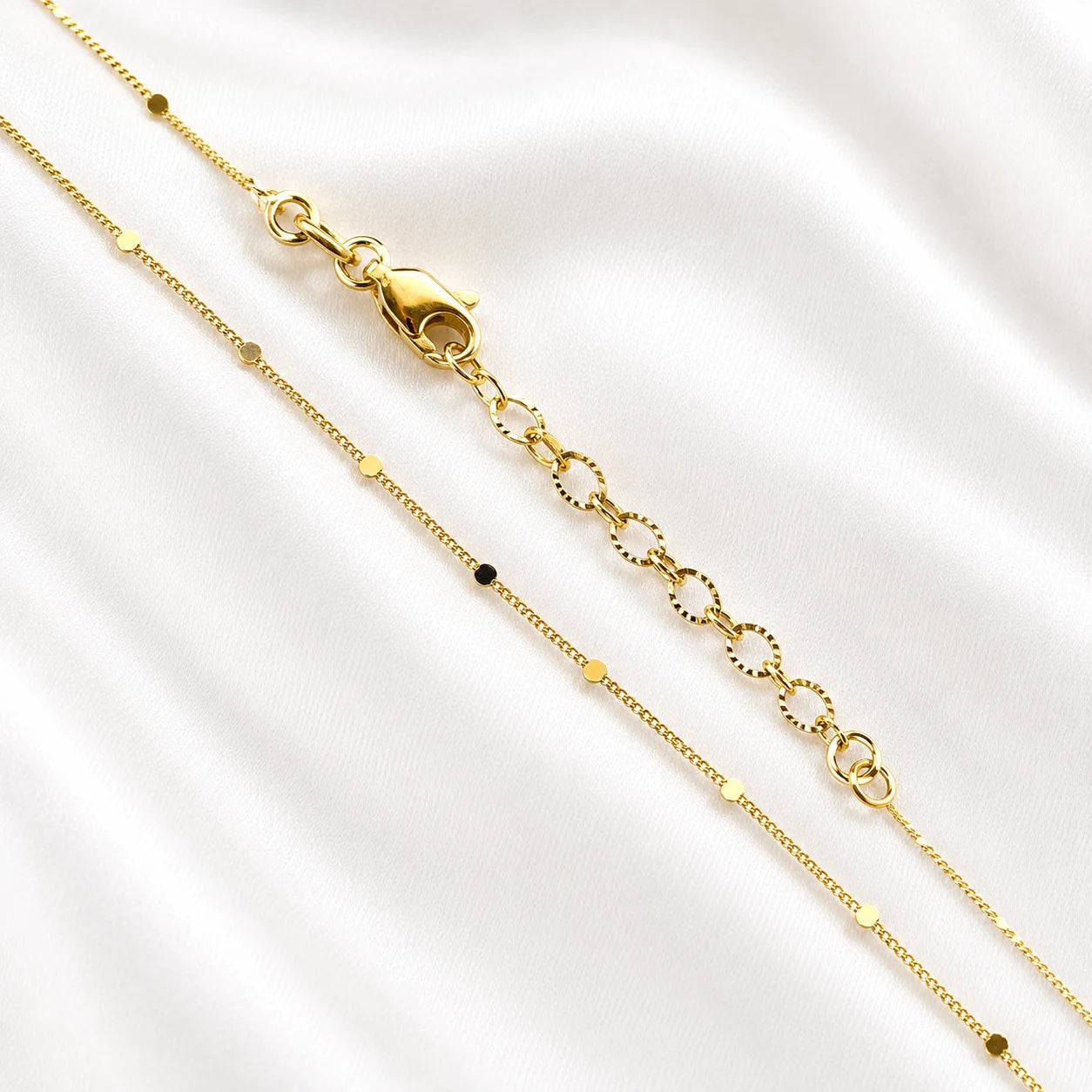 Flat lay of Ma Vie dainty curb chain necklace on cream silk, 18k gold filled pressed detail