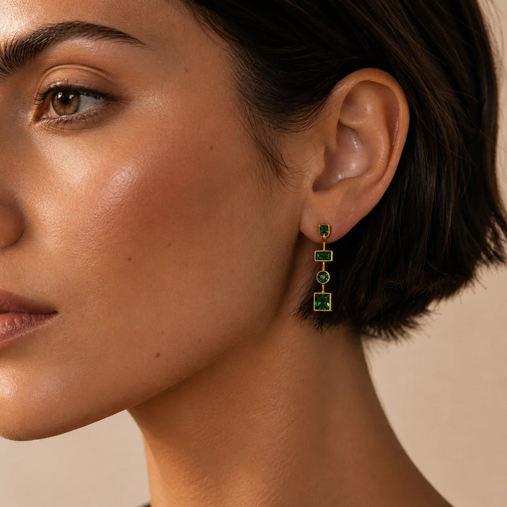 Woman wearing Ma Vie emerald drop earrings 18k gold filled with green CZ geometric design