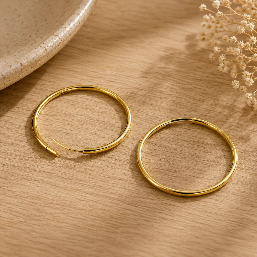 Close-up of round 18K gold-filled hoop earrings on ivory fabric