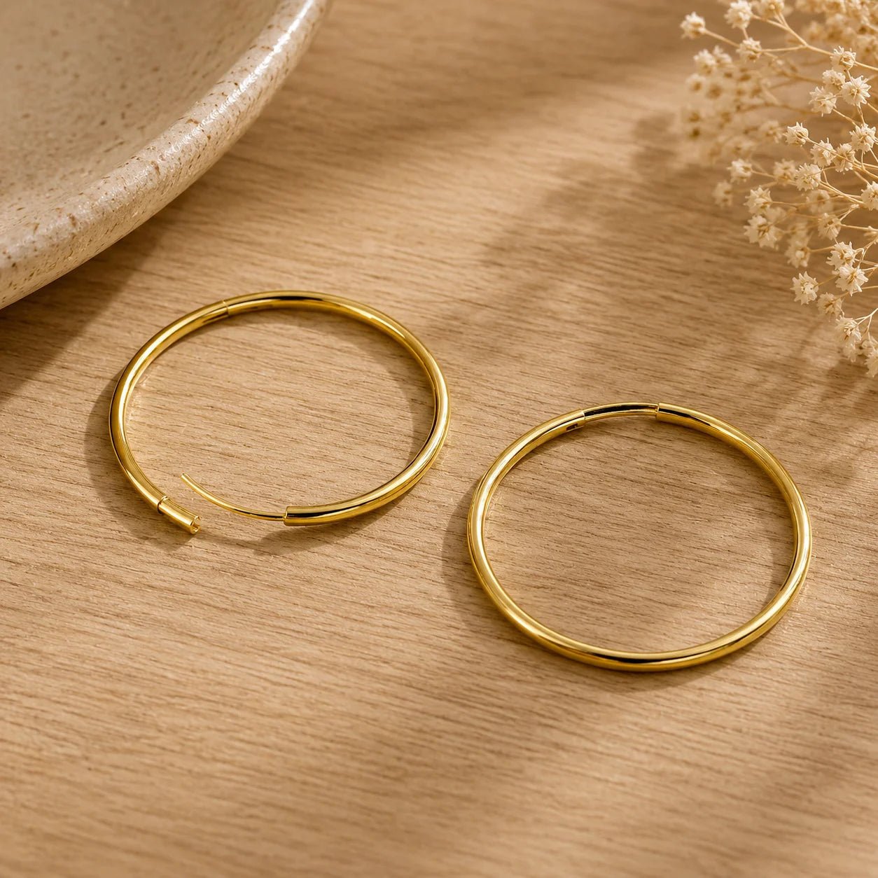 Close-up of round 18K gold-filled hoop earrings on ivory fabric