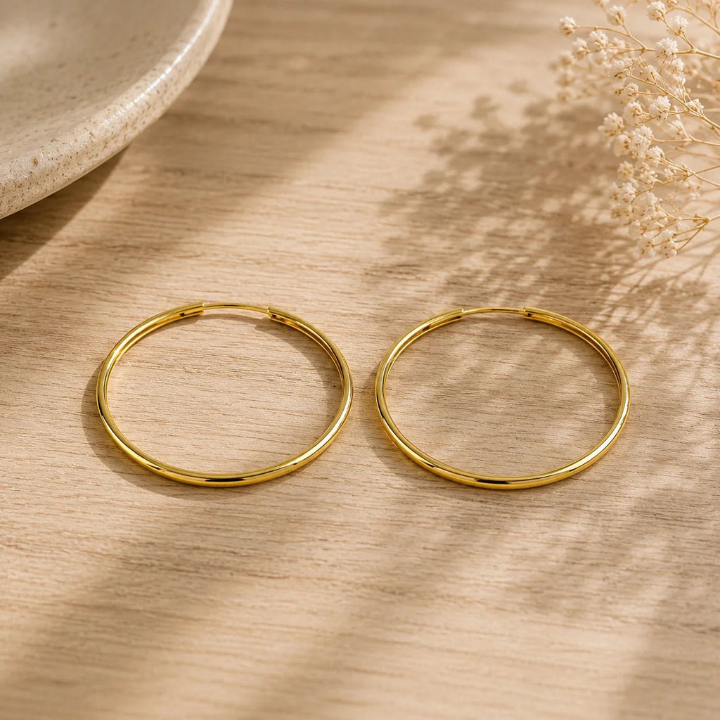 18K gold-filled hoop earrings displayed on cream fabric