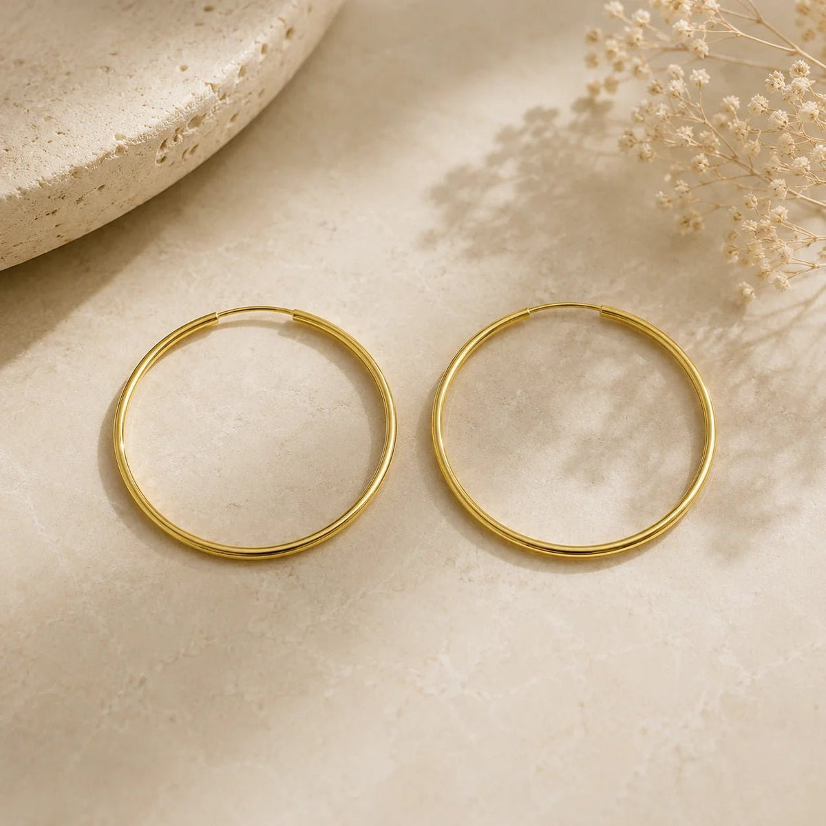 Large gold-filled endless hoop earrings displayed on cream fabric