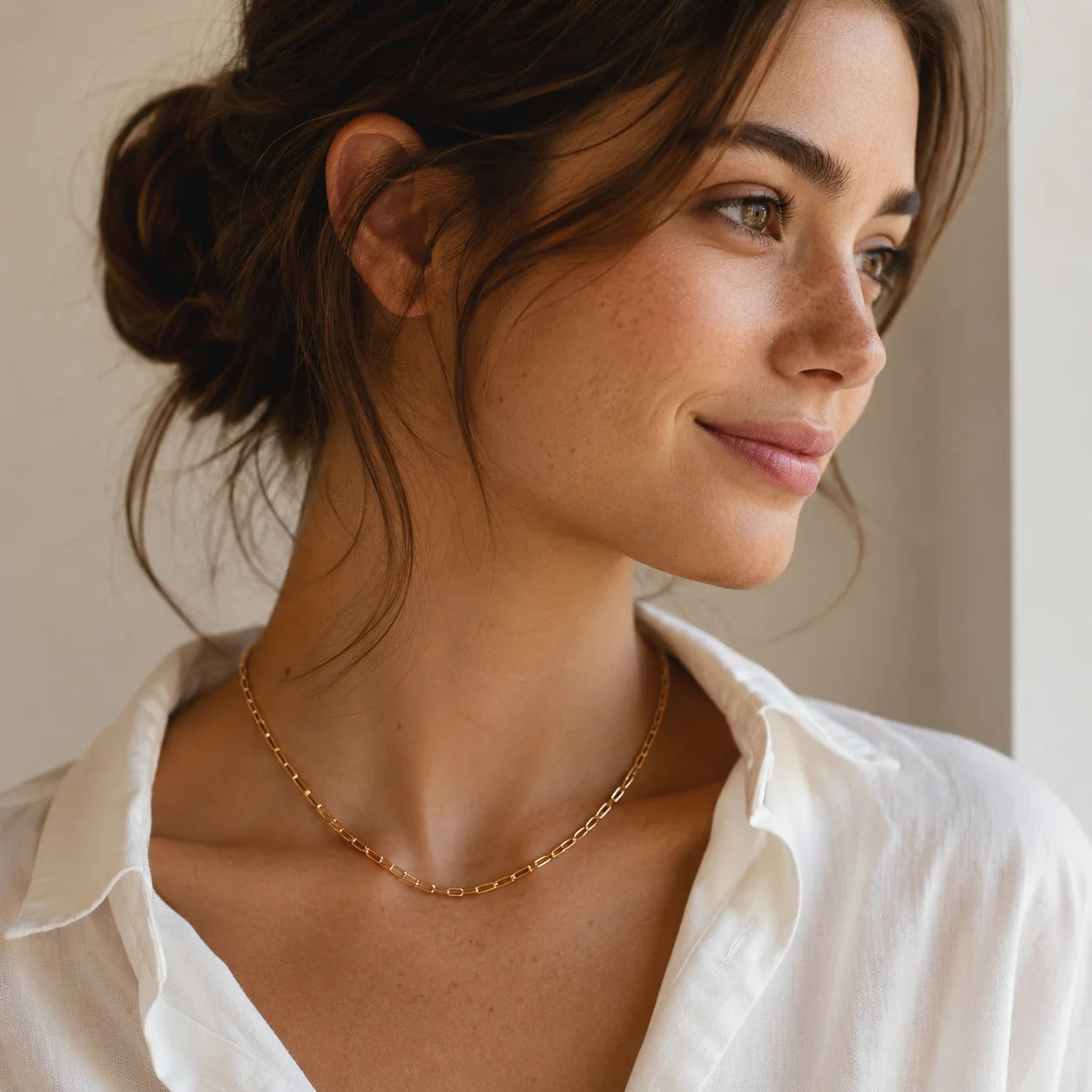 Woman in white blouse wearing dainty gold paperclip chain necklace, everyday styling