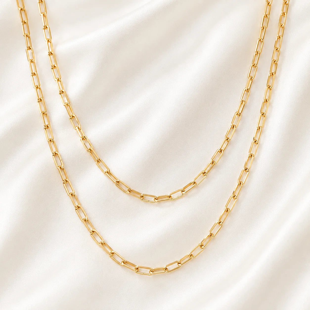 Close up of 18k gold filled paperclip link chain showing flat polished oval links on gold silk