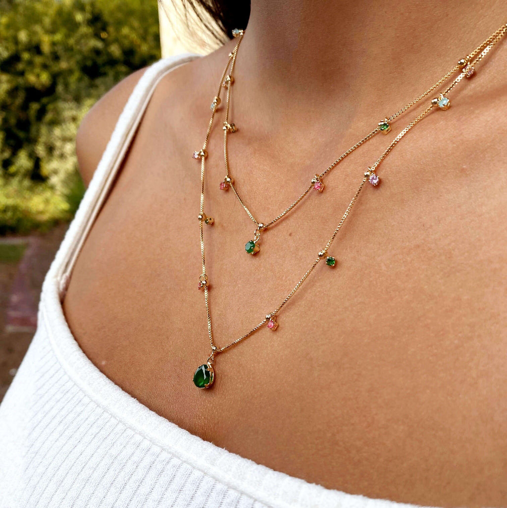 Side view of multicolor layered teardrop necklace with green pendant