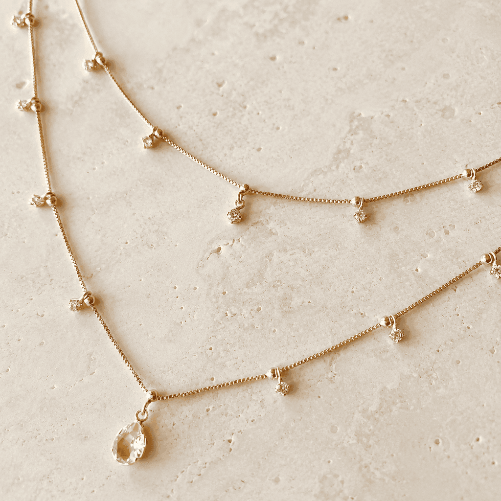 Nude pink layered teardrop necklace with cubic zirconia accents on ivory stone