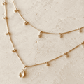 Nude pink layered teardrop necklace with cubic zirconia accents on ivory stone