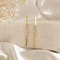 Linear drop earrings in 18K gold-filled displayed on ivory fabric