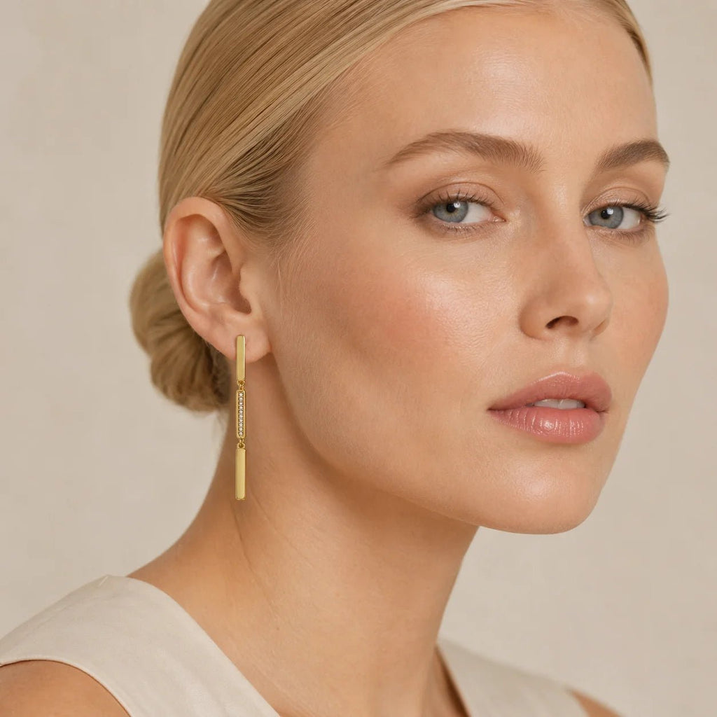 Blonde model wearing linear drop earrings in 18K gold-filled