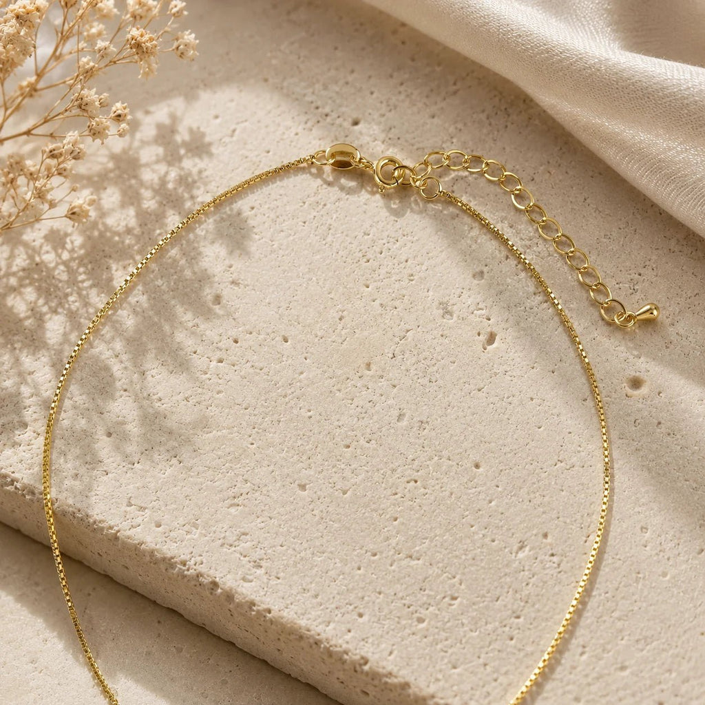 Close-up of triple bar pendant and pavé CZ detail on beige fabric