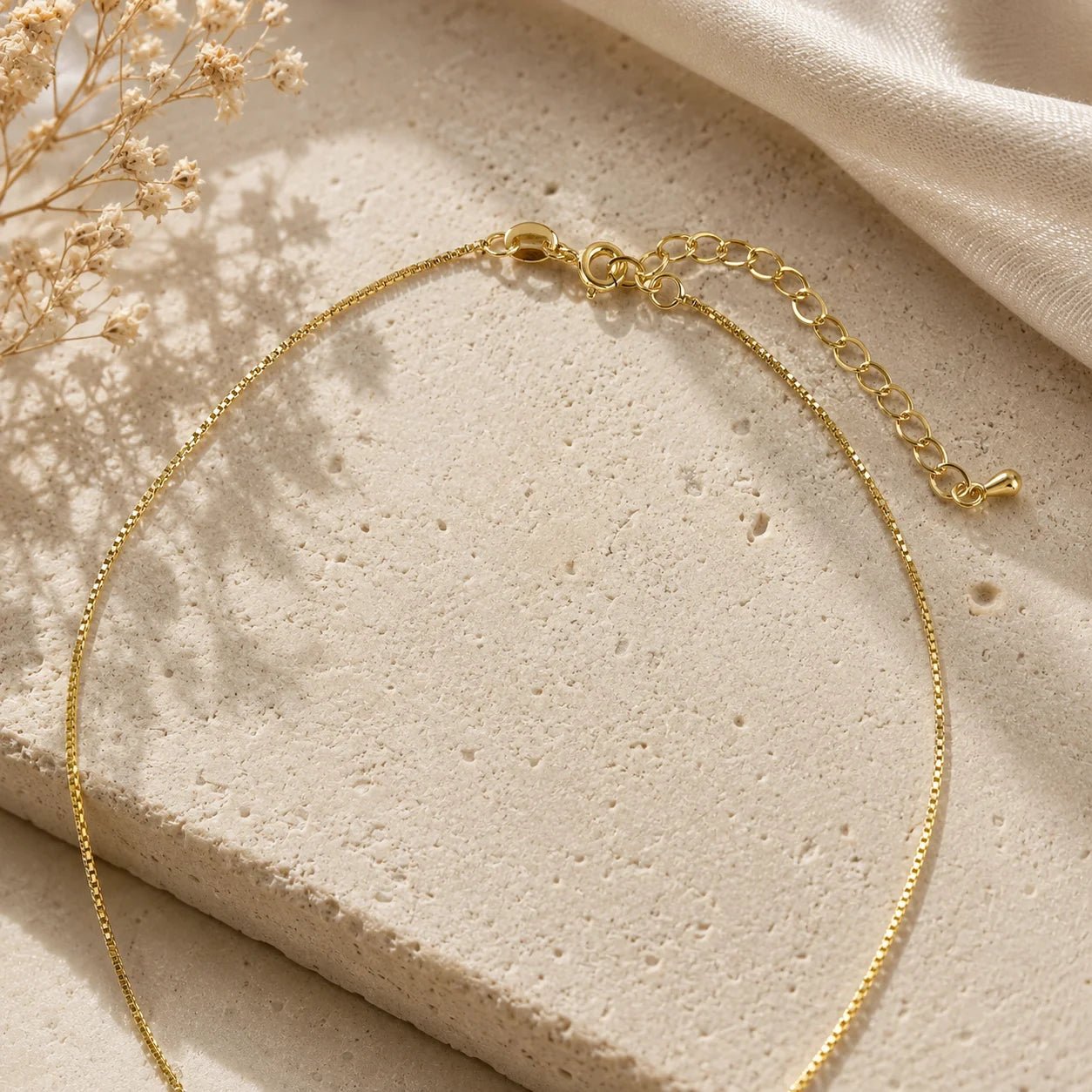 Close-up of triple bar pendant and pavé CZ detail on beige fabric