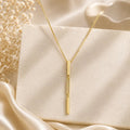18K gold-filled triple bar drop necklace displayed on ivory fabric