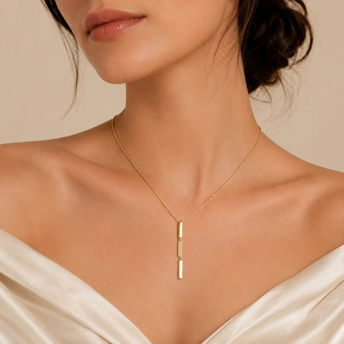 Model wearing gold-filled triple bar drop necklace with white neckline