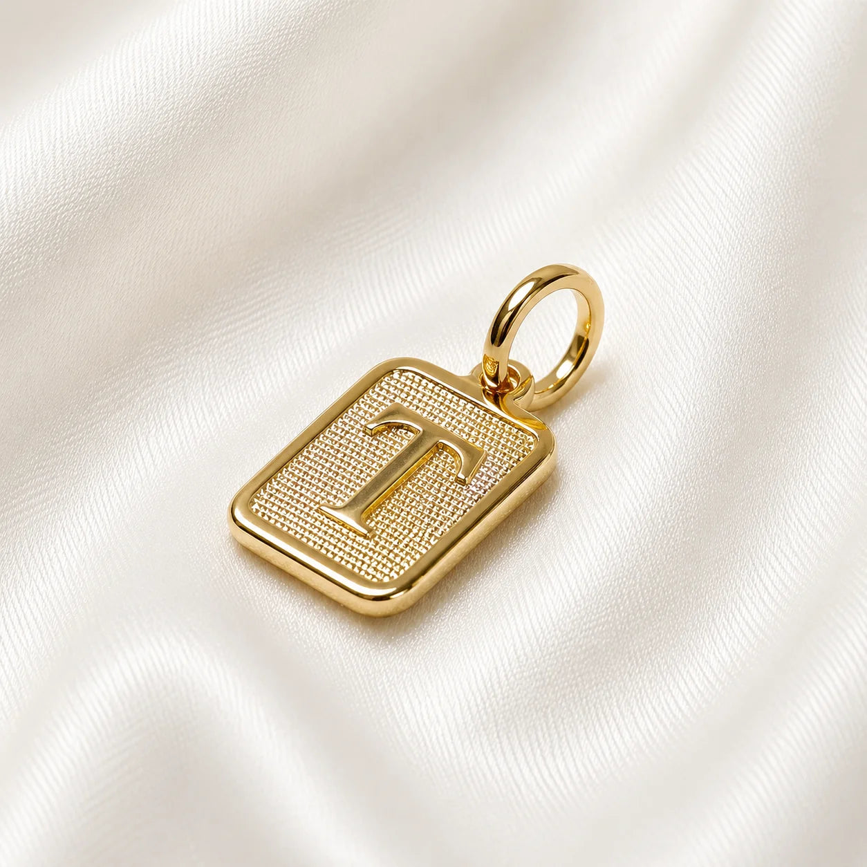 Monogram initial charm, square 18k gold filled pendant resting on cream silk