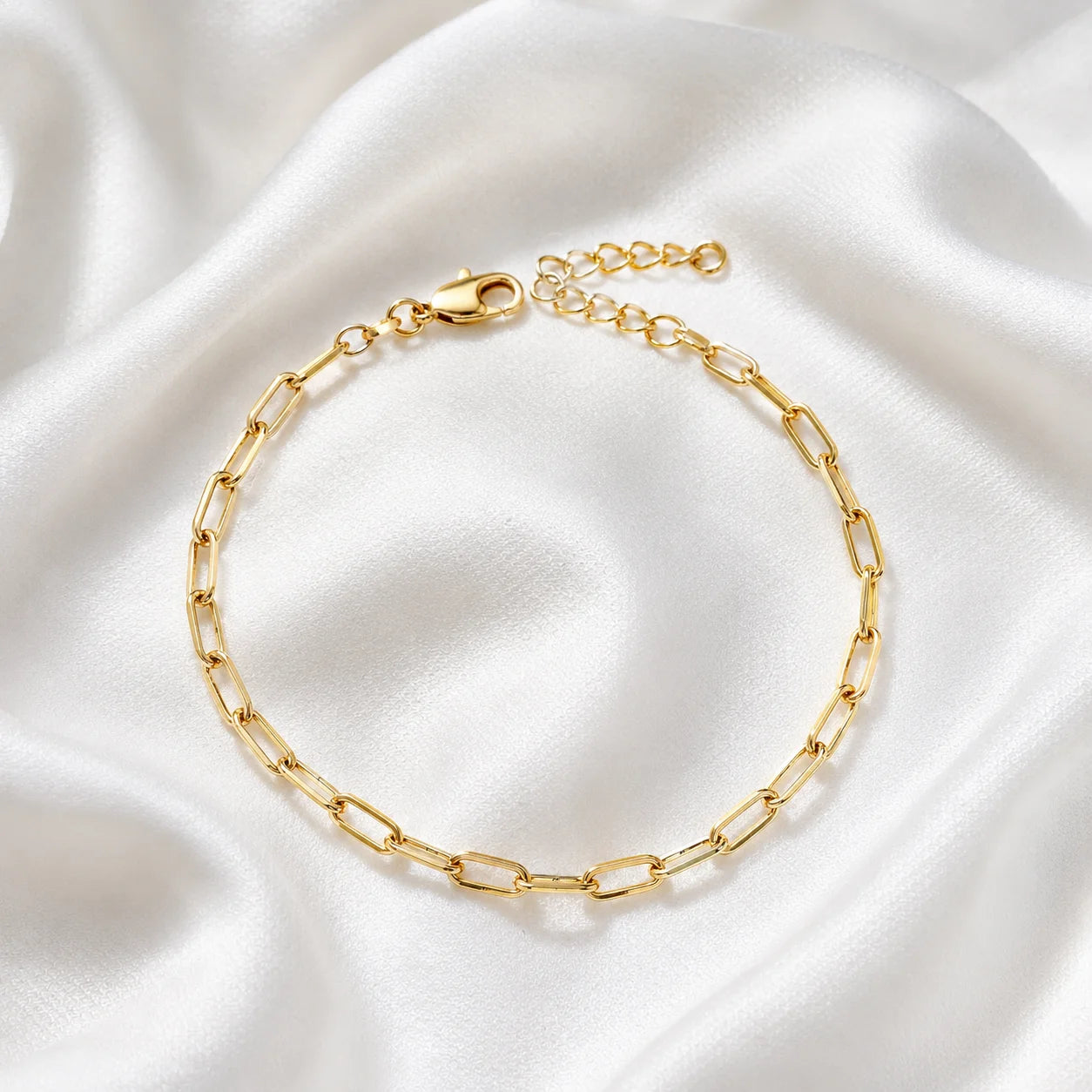 Flat lay of Ma Vie paperclip chain bracelet on cream silk, 18k gold filled dainty stackable