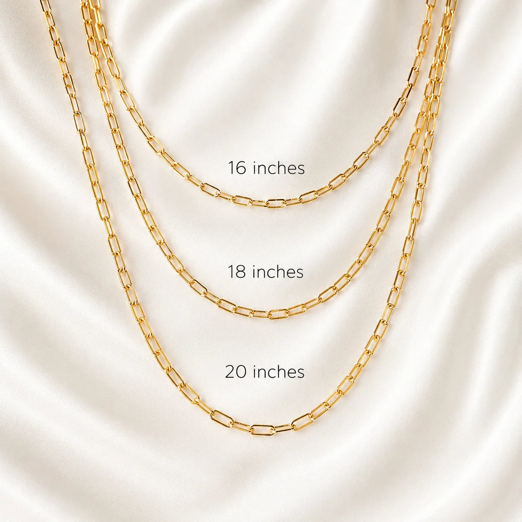 Layered 18k gold filled paperclip link necklaces displayed flat on ivory silk, three lengths
