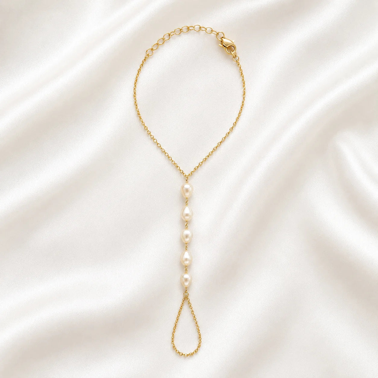 Close up of Ma Vie pearl hand chain bracelet, 18k gold filled with imitation baroque pearl charm
