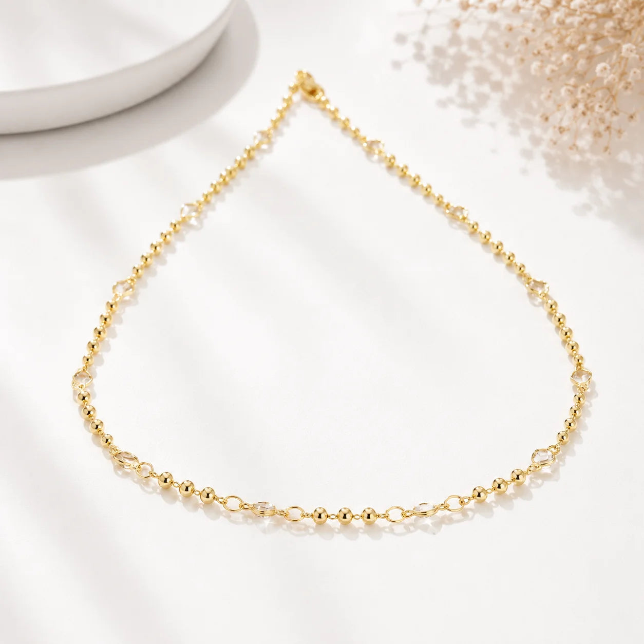 Polished gold bead CZ necklace, bezel-set cubic zirconia stations on white