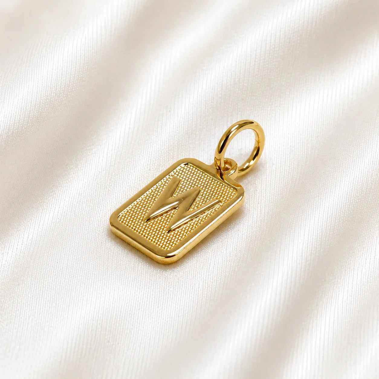 Square monogram pendant in 18k gold filled, side angle on silk, custom letter charm